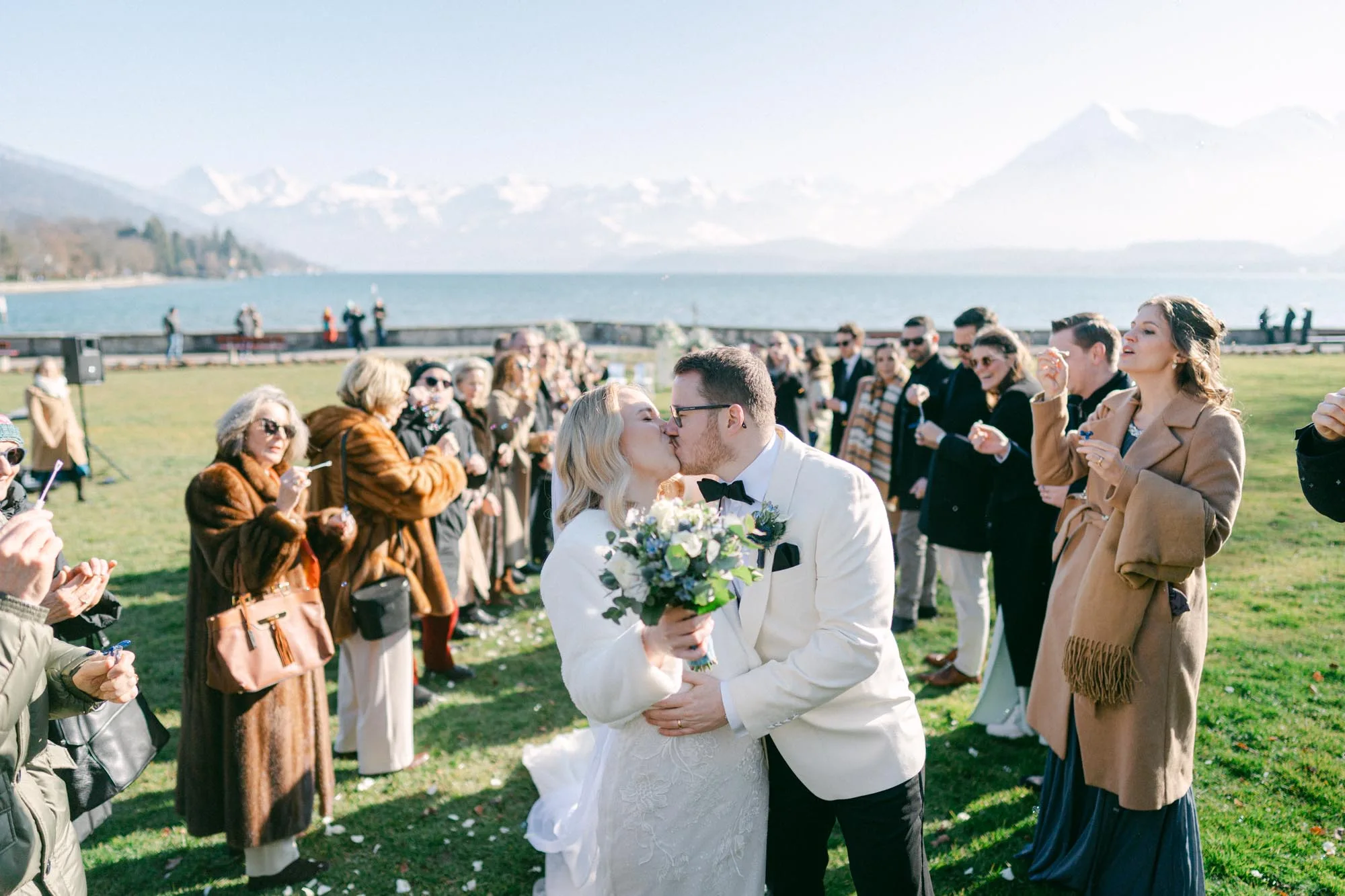 Wedding couple kissing in front of Lake Thun and the Alps at Schloss Schadau, Switzerland